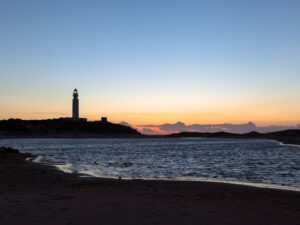 A captivating depiction of Cape Trafalgar’s lighthouse, elegantly silhouetted against the canvas of a sunset sky,