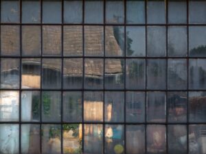 A print capturing an old cottage window in Southern Czechia, mirroring a mosaic of reflections through its unique square glass plates.