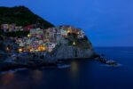 This striking image This image encapsulates a serene twilight moment in Manarola, where the first hints of evening lights begin to sprinkle the town, creating a magical ambiance. a solitary figure amidst the historic beauty of Cadiz, offering a tale of reflection and timelessness.