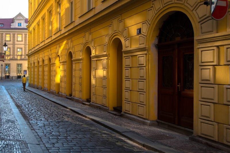 A vivid depiction of Prague at dawn, capturing the golden light that graces the facade of a classic Czech building.