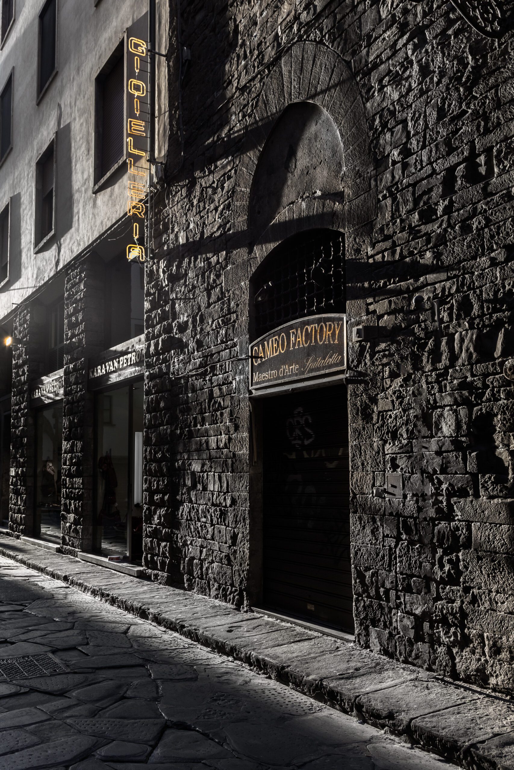 Sunlit street in Florence with historic stone buildings.