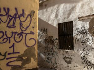 Graffiti-covered walls in a sunlit alleyway of Malaga