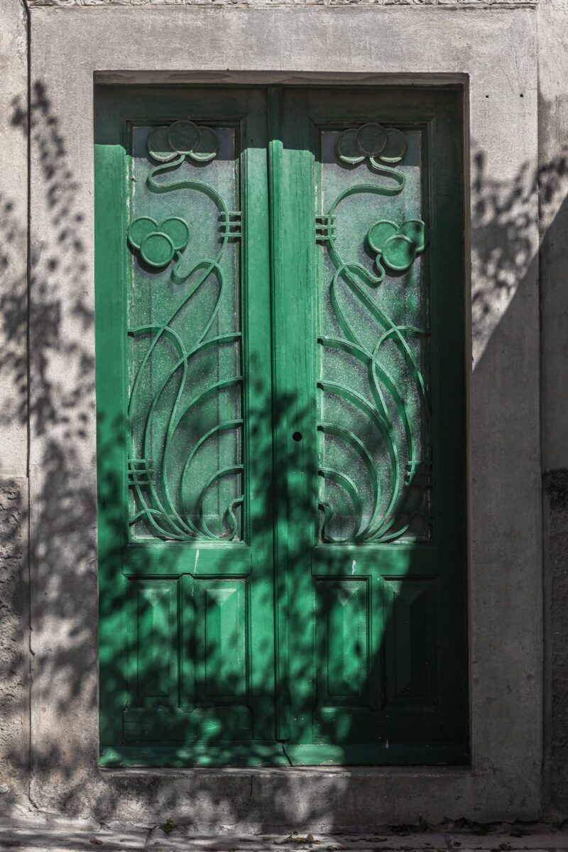 Emerald green door in Chora, Mykonos with intricate patterns.