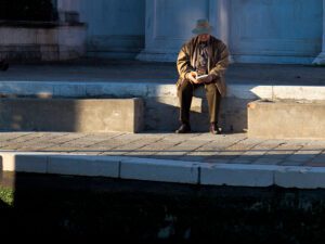 Man sitting by Venice's Grand Canal with historic architecture in the background.