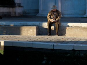 Man sitting by Venice's Grand Canal with historic architecture in the background.