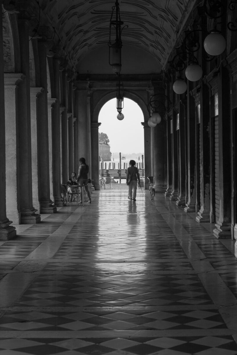Black and white photograph of St. Marks Plaza, Venice with person walking.