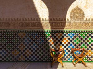 Ornate Alhambra Castle detailing with two wooden chairs in the foreground.