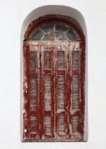 Aged red door with arched window in Mykonos.