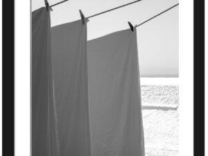White sheets billowing in the wind resembling sails, set against a bright background in Fira, Santorini.