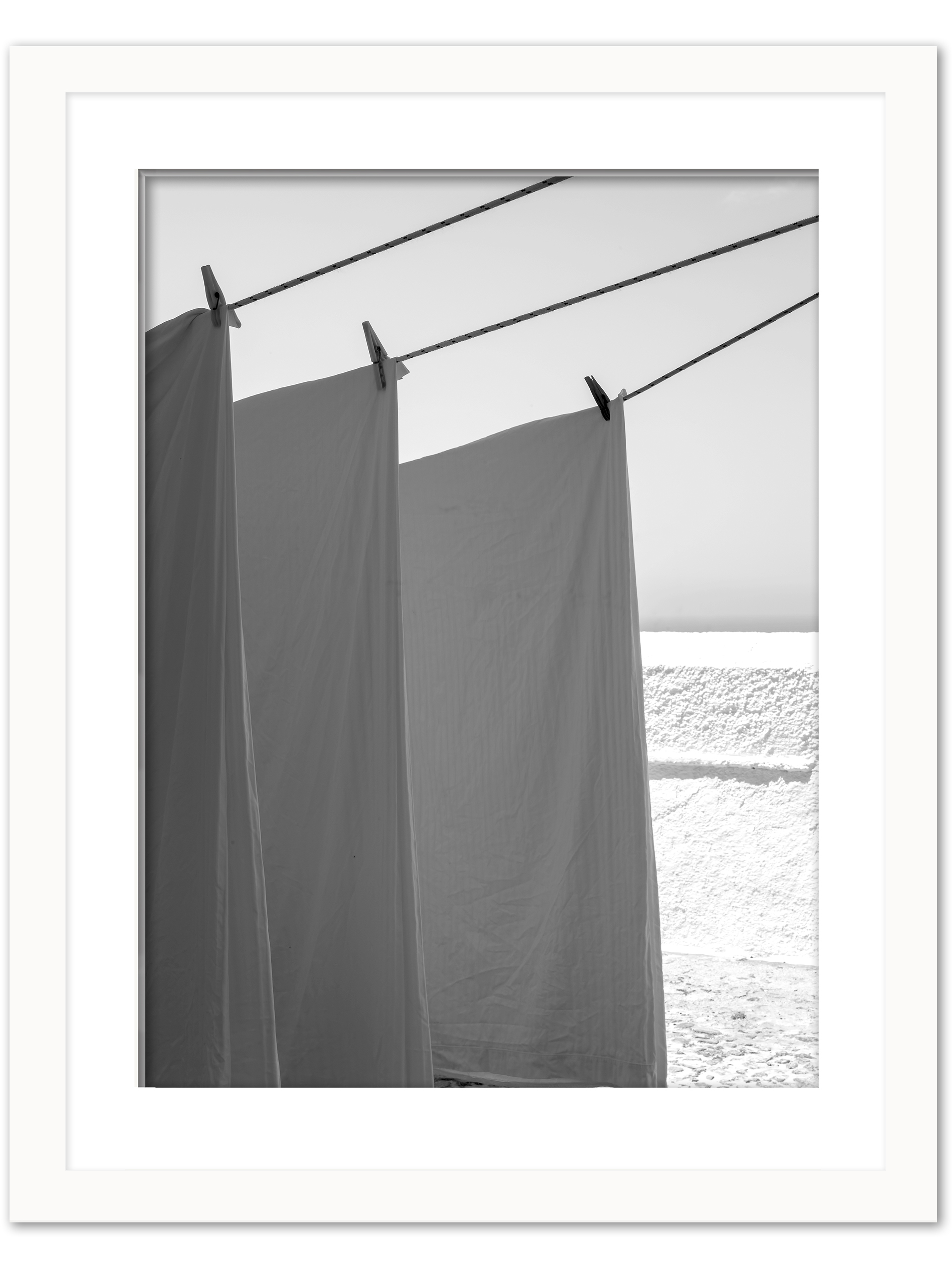 White sheets billowing in the wind resembling sails, set against a bright background in Fira, Santorini.