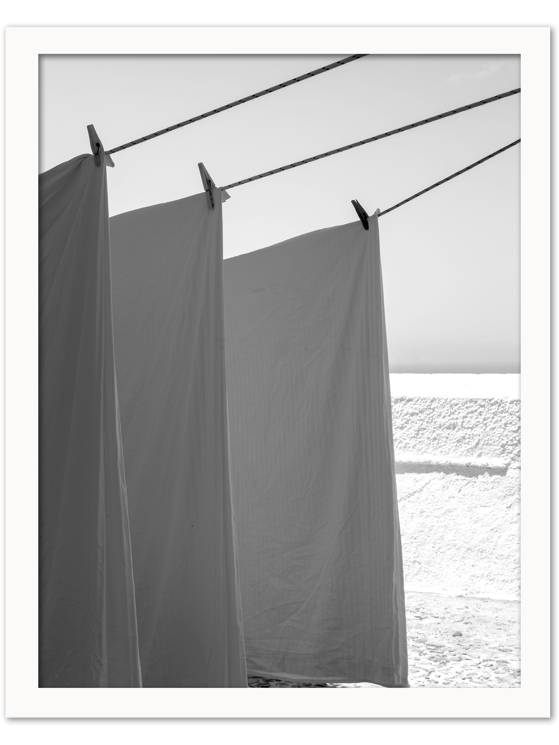 White sheets billowing in the wind resembling sails, set against a bright background in Fira, Santorini.