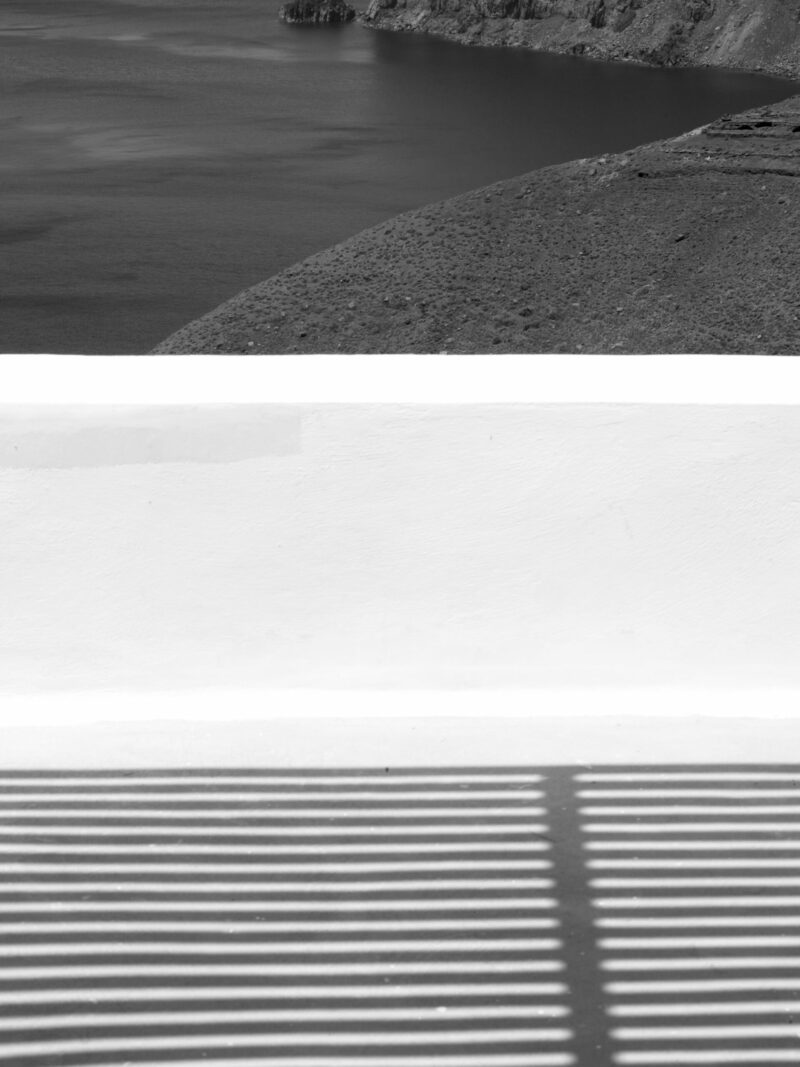 Dramatic geometric shadows cast across a balcony in Santorini, Greece.