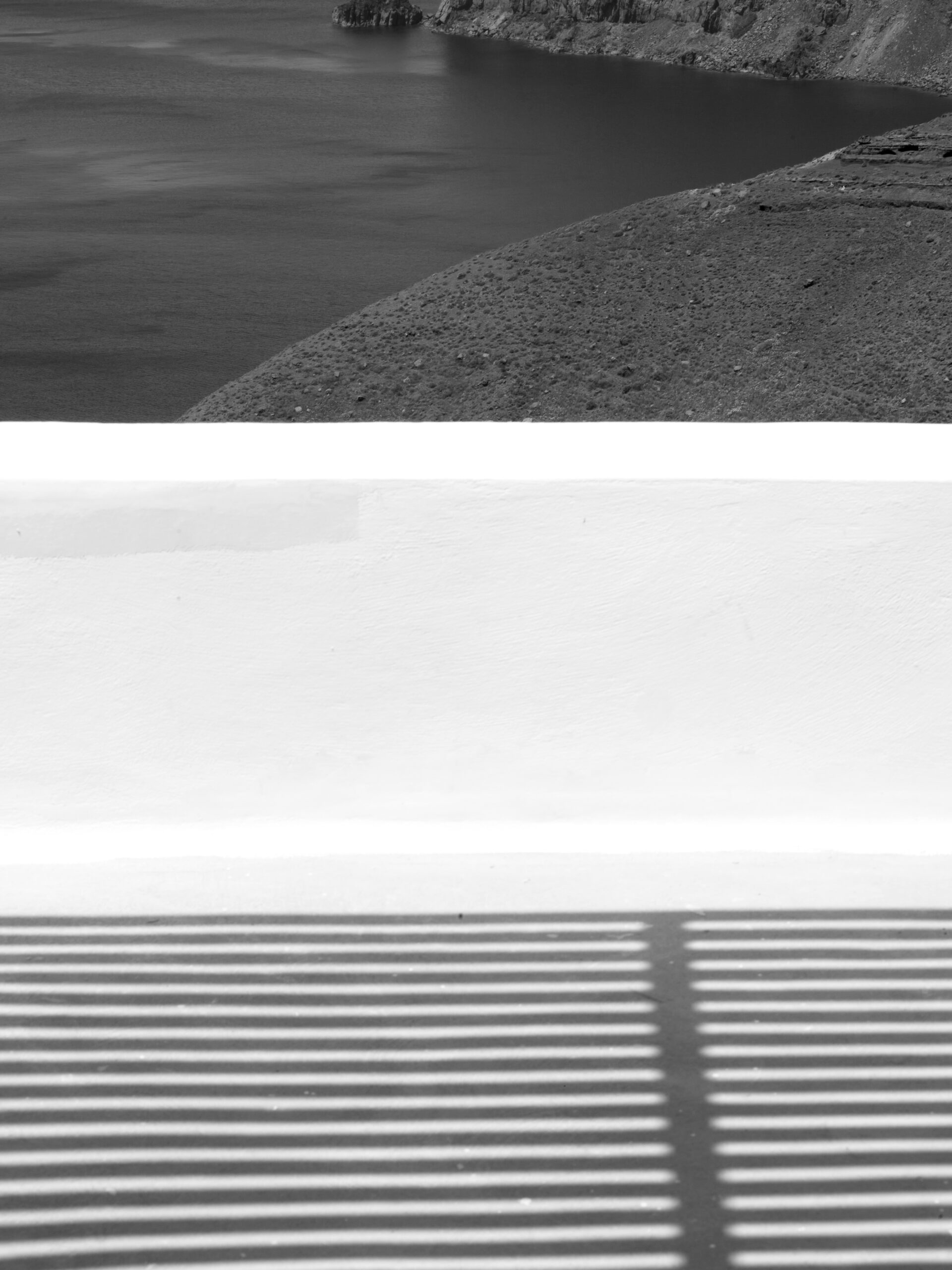 Dramatic geometric shadows cast across a balcony in Santorini, Greece.