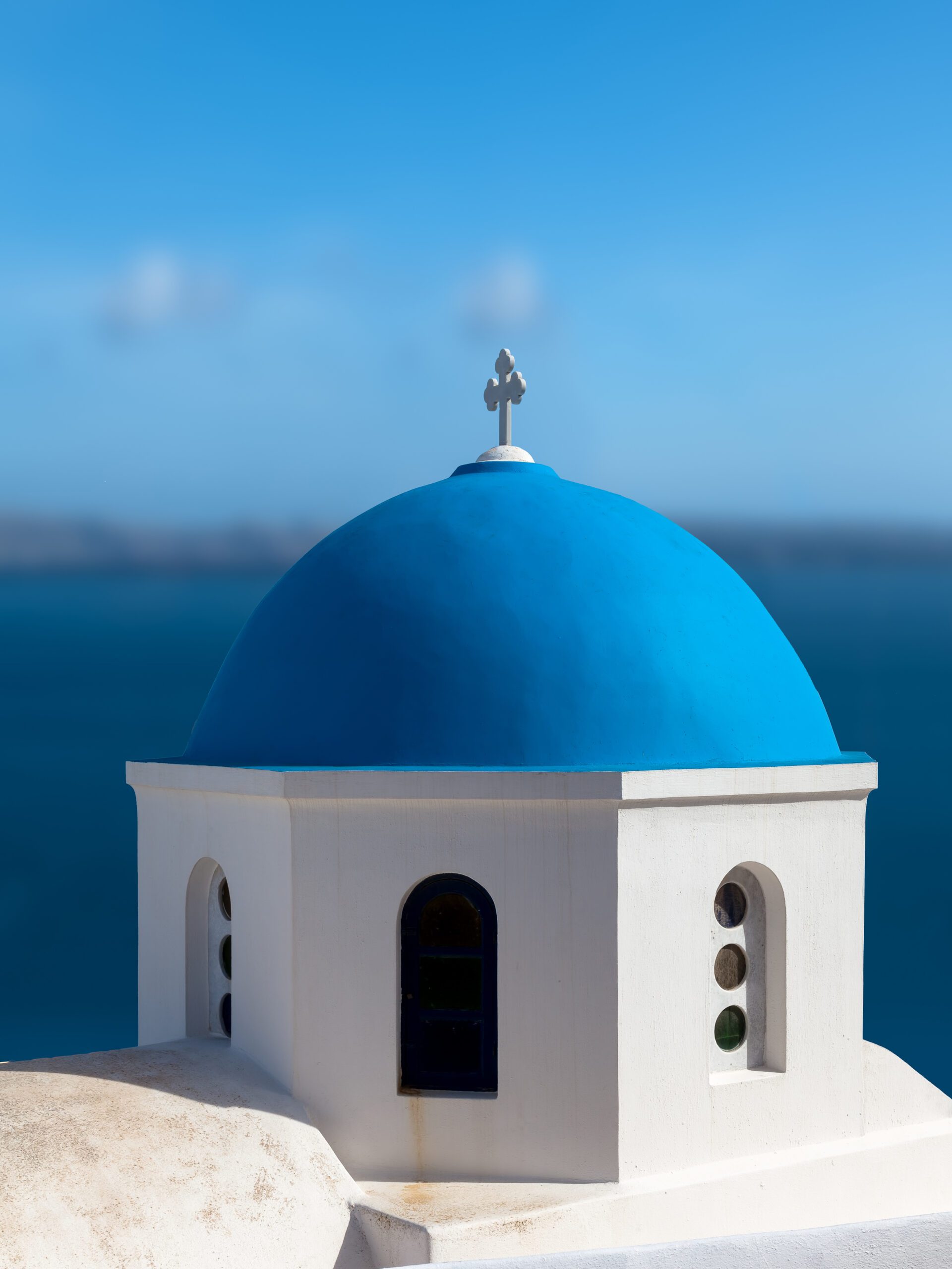 Blue domed church in Santorini overlooking the serene blue waters of the caldera.