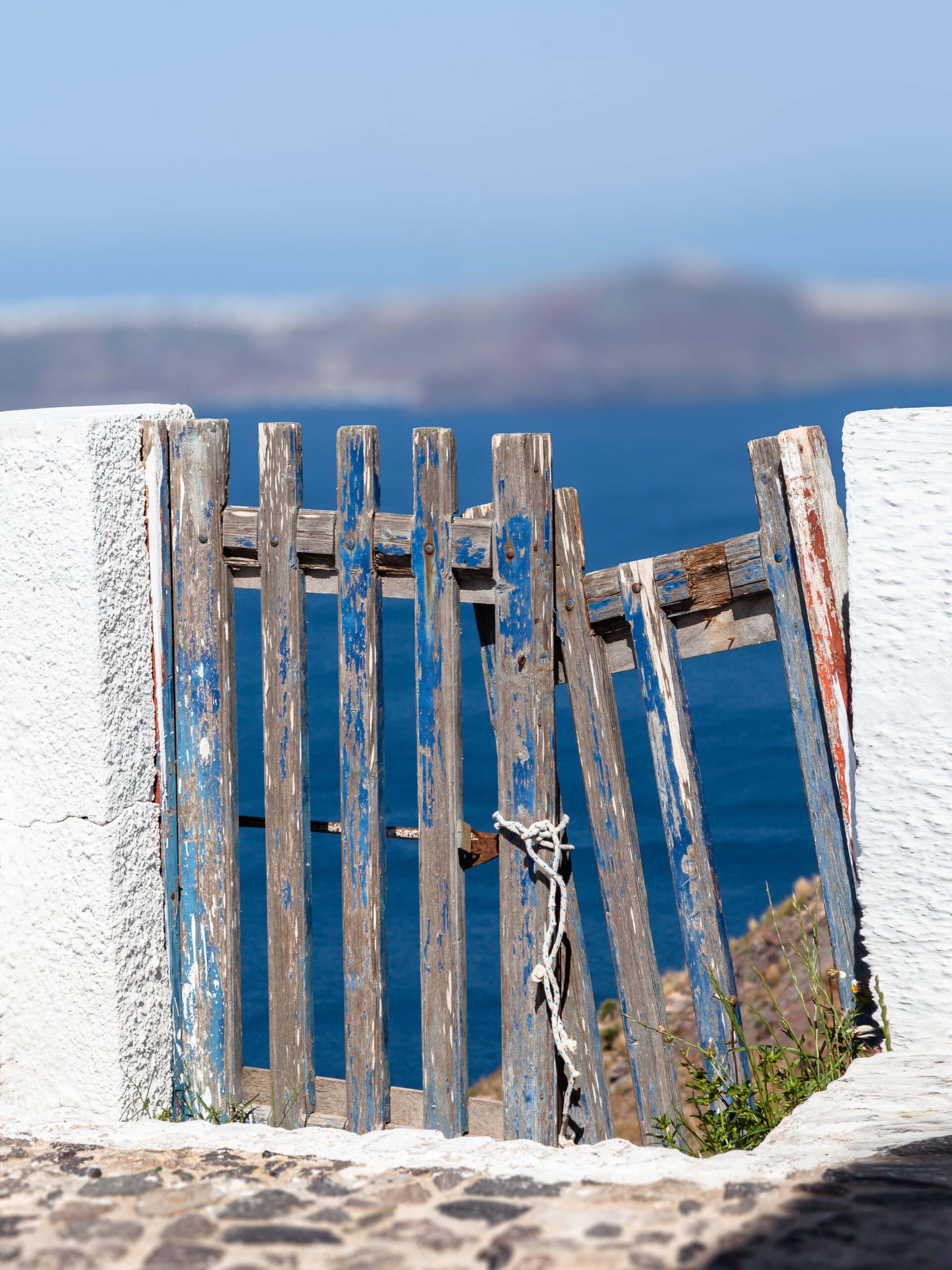 Weathered blue wooden fence with ocean view in Santorini, Greece.