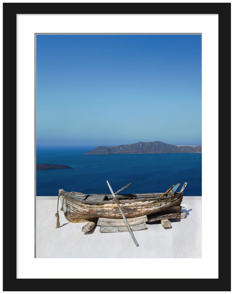 Old rowboat on a white rooftop overlooking the blue caldera in Santorini.