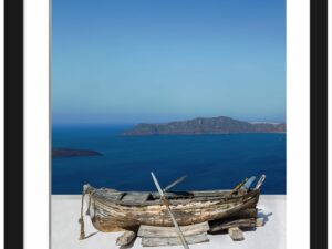 Old rowboat on a white rooftop overlooking the blue caldera in Santorini.