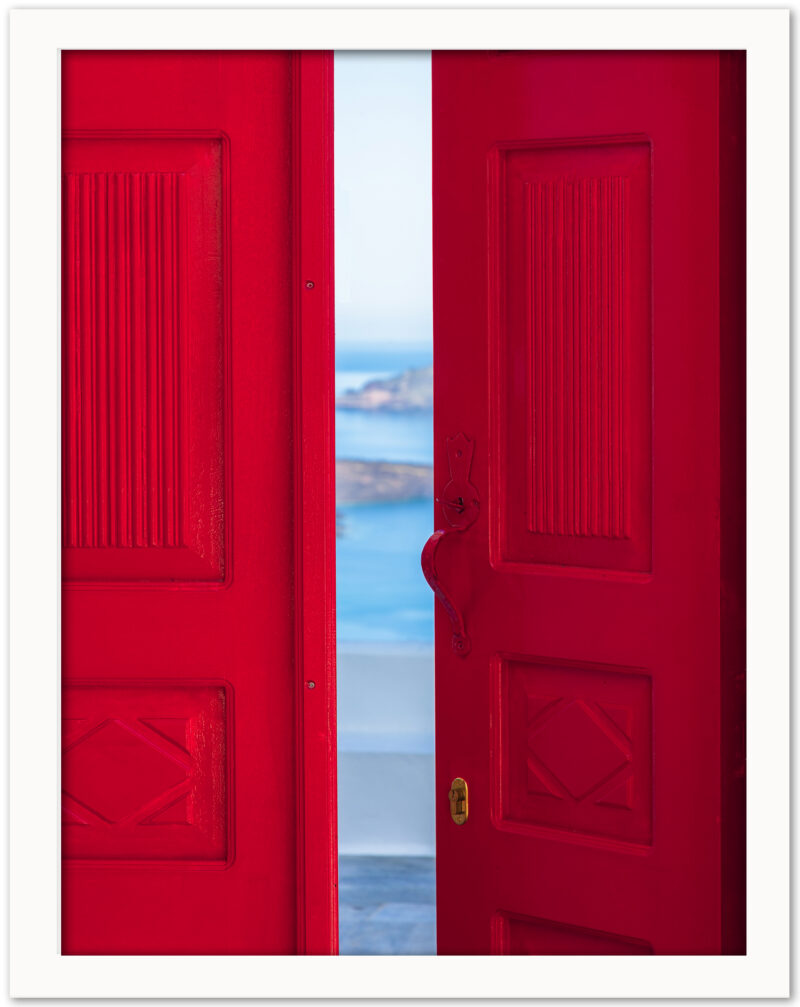 Bright red doorway opening to a view of the Santorini caldera with blue waters below.