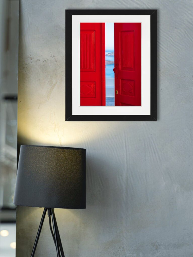 Bright red doorway opening to a view of the Santorini caldera with blue waters below.