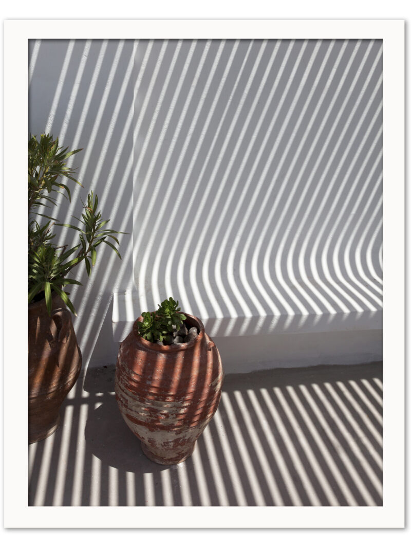 Clay pots on a Santorini balcony with dramatic geometric shadows cast by the sunlight.