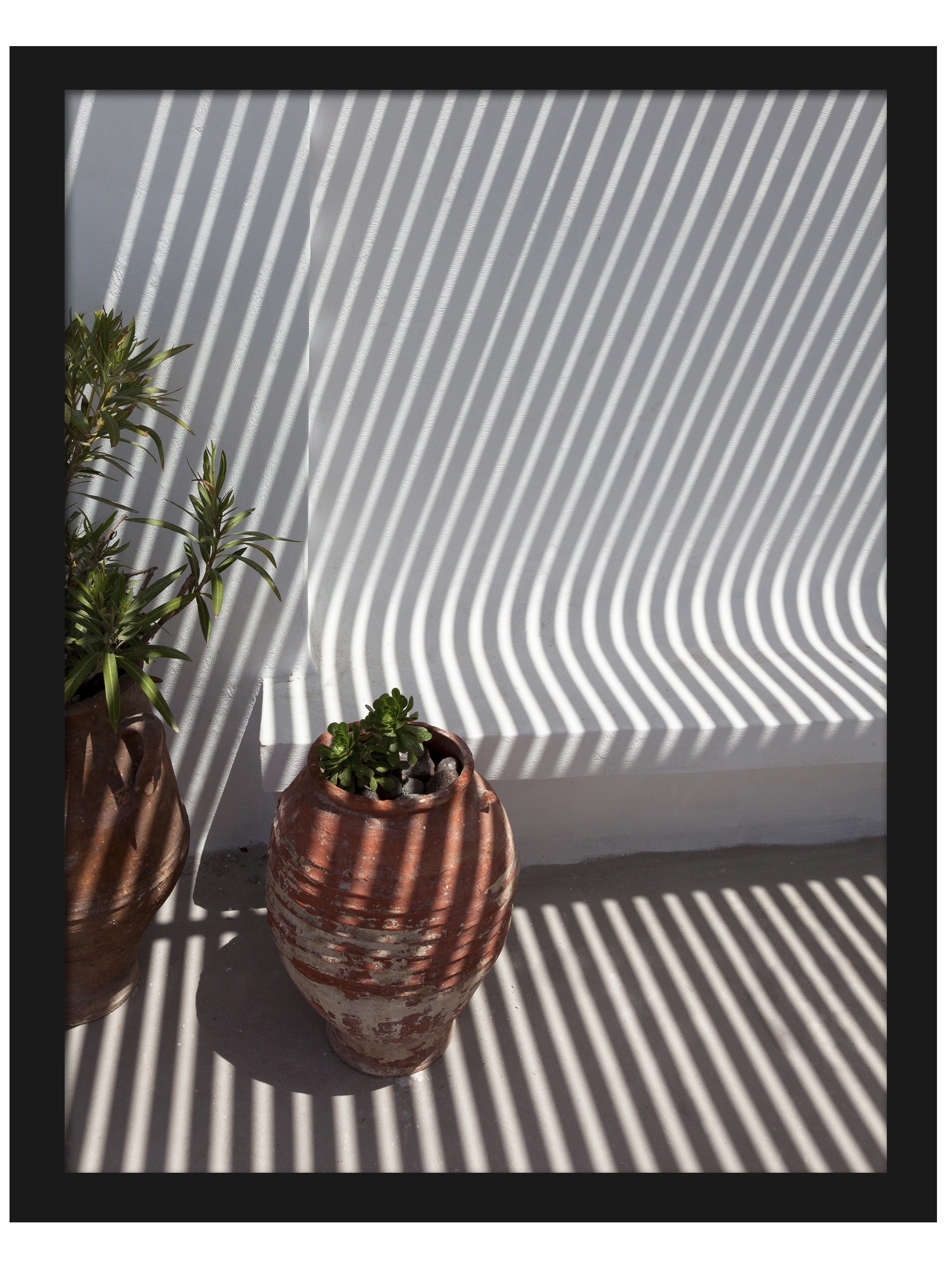 Clay pots on a Santorini balcony with dramatic geometric shadows cast by the sunlight.