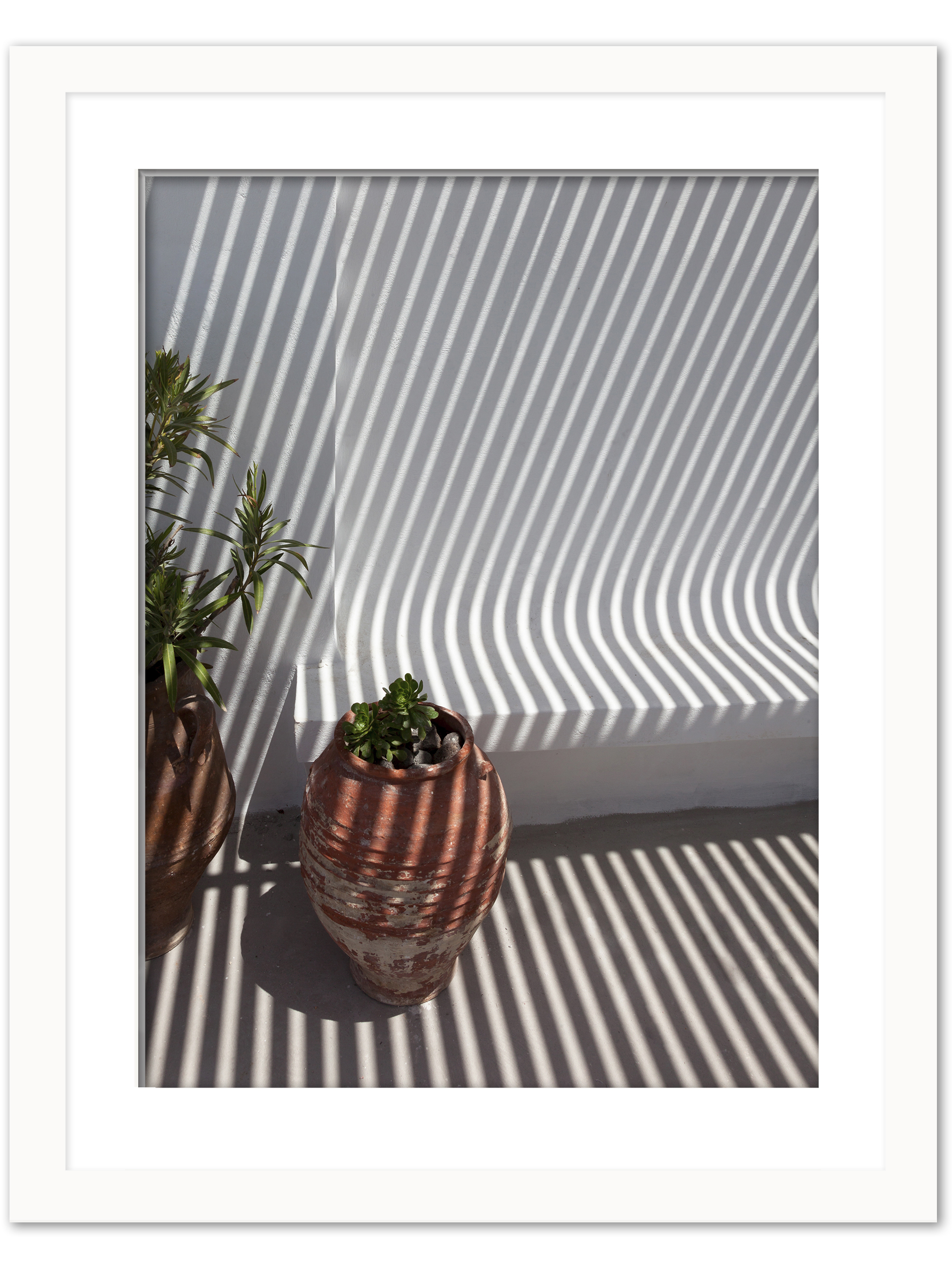 Clay pots on a Santorini balcony with dramatic geometric shadows cast by the sunlight.