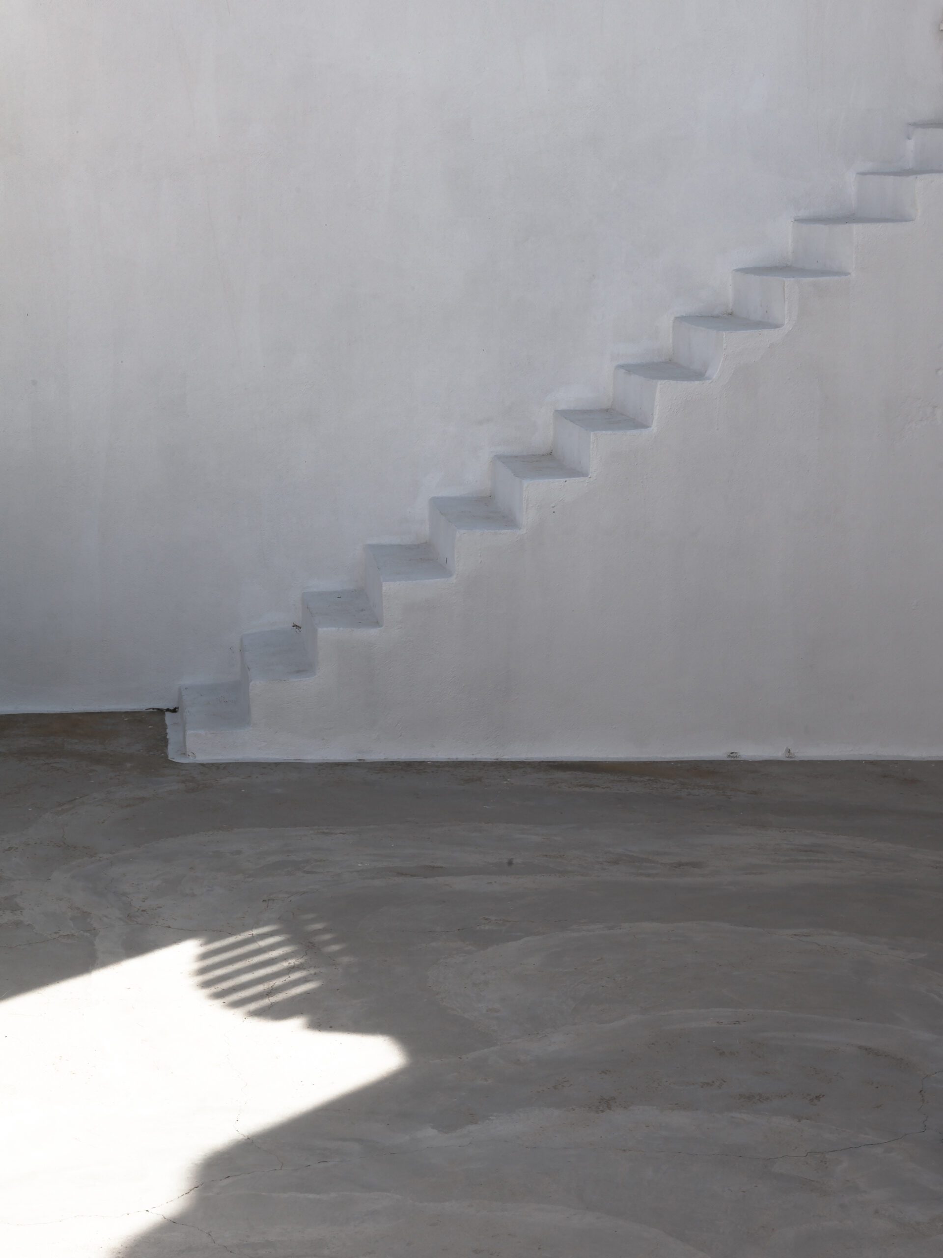 White staircase with shadow play in a whitewashed building in Santorini, Greece.