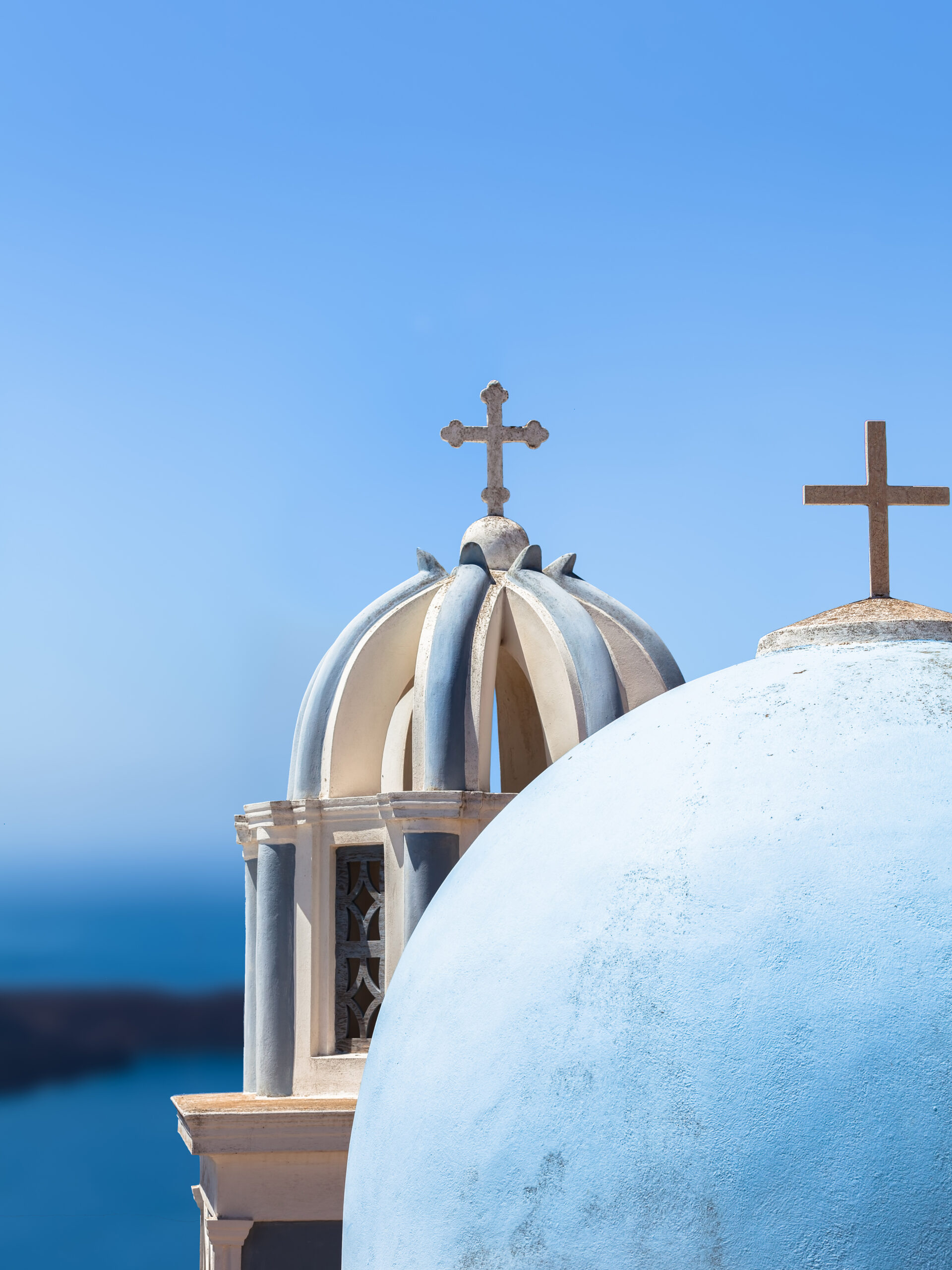 Iconic blue church domes under the clear sky in Santorini, Greece.