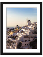 The village of Oia in Santorini, Greece, captured at dusk with soft golden lighting illuminating the iconic windmills and white buildings.