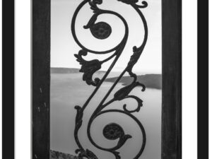 Black and white photo of an old iron gate with a view of the Santorini caldera.