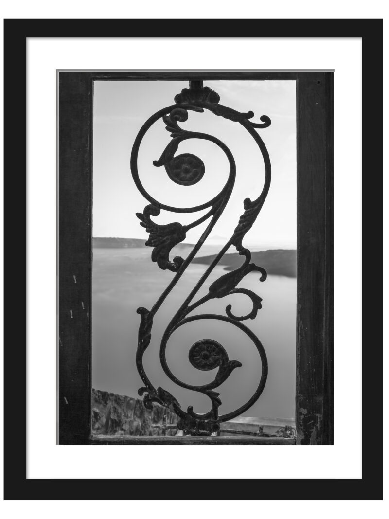 Black and white photo of an old iron gate with a view of the Santorini caldera.