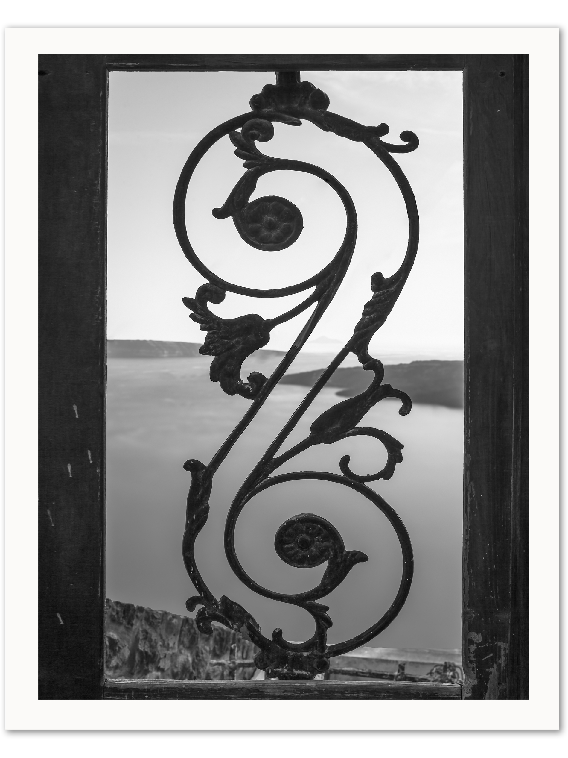 Black and white photo of an old iron gate with a view of the Santorini caldera.