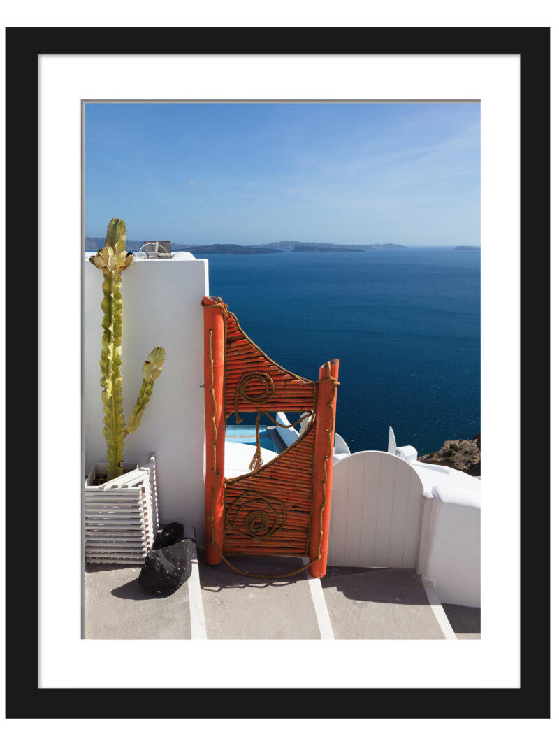 Vibrant orange gate in Fira, Santorini overlooking the clear blue caldera waters.