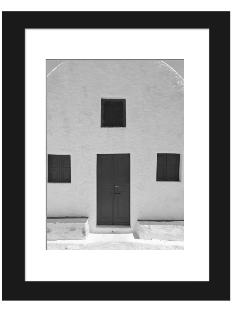 Simple white house in Santorini with symmetric windows and a minimalist design.