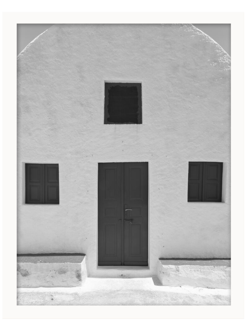 Simple white house in Santorini with symmetric windows and a minimalist design.